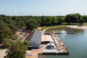 Horecaterras onder zandkleurige tent met uitzicht op water